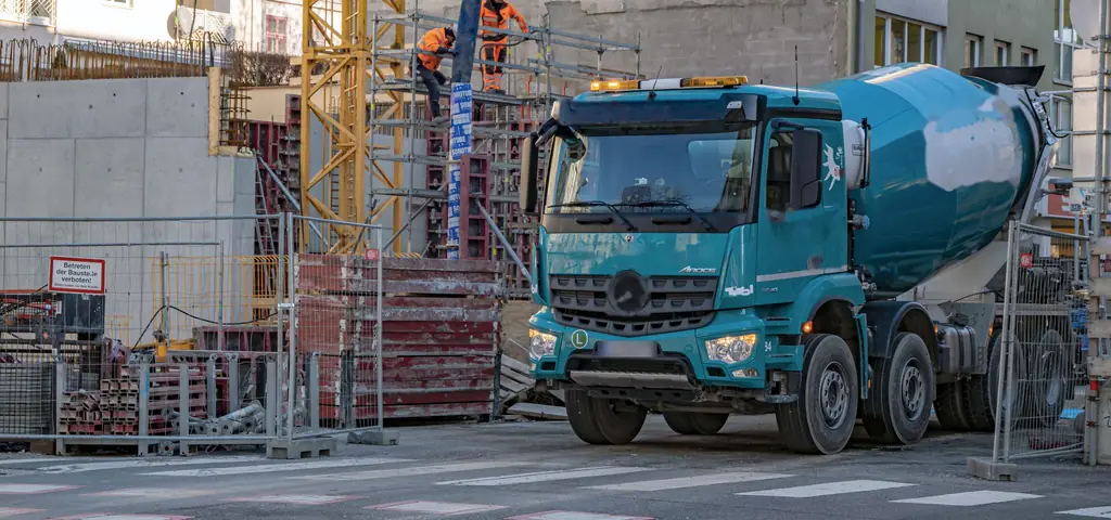 Современный автобетоносмеситель у строящегося дома